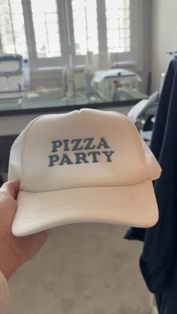 White trucker hat with Pizza Party embroidered in blue block letters
