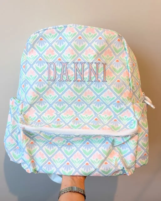 A pastel floral-diamond kids backpack with the name Danni embroidered across the front